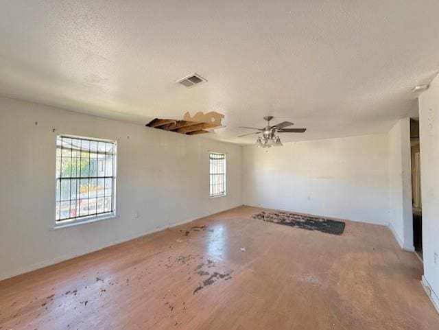 empty room with visible vents, ceiling fan, a textured ceiling, and wood finished floors