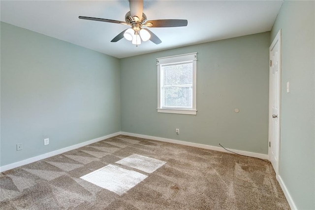 carpeted spare room with a ceiling fan and baseboards