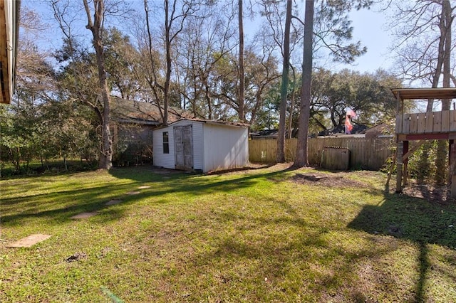 view of yard featuring fence, a storage unit, and an outbuilding