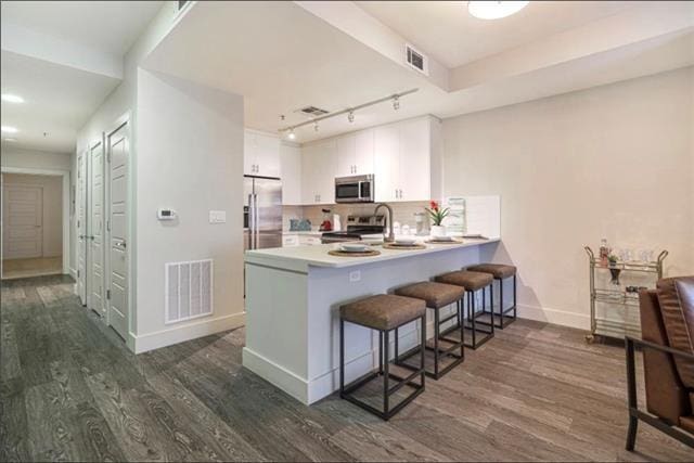 kitchen with stainless steel appliances, light countertops, visible vents, and white cabinetry