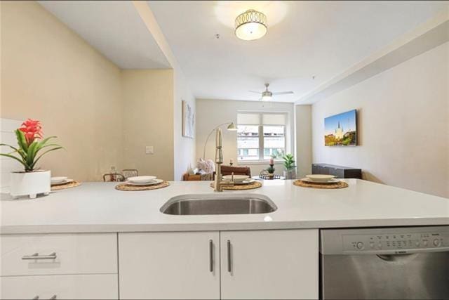 kitchen with a sink, white cabinetry, open floor plan, light countertops, and stainless steel dishwasher