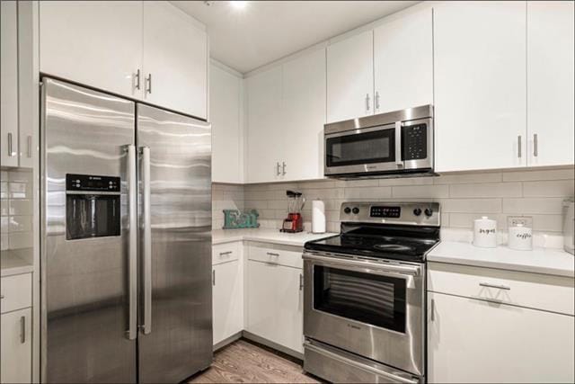kitchen with light countertops, appliances with stainless steel finishes, backsplash, and white cabinets