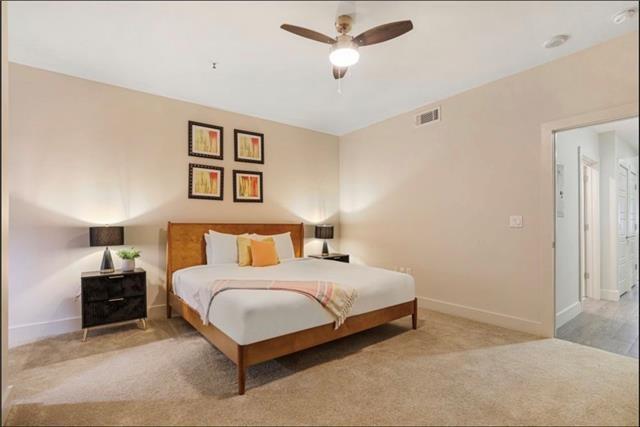 bedroom with a ceiling fan, visible vents, light carpet, and baseboards