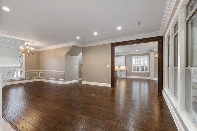 unfurnished living room featuring ornamental molding, visible vents, dark wood finished floors, and an inviting chandelier