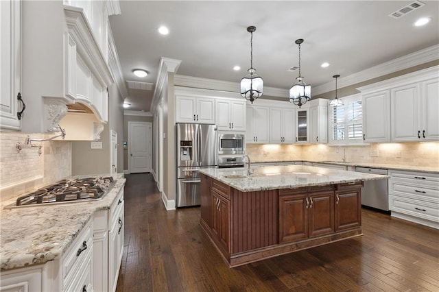 kitchen with appliances with stainless steel finishes, an island with sink, and white cabinetry