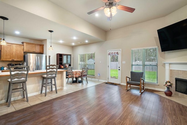 interior space with light countertops, hanging light fixtures, light wood-style flooring, freestanding refrigerator, and a kitchen breakfast bar