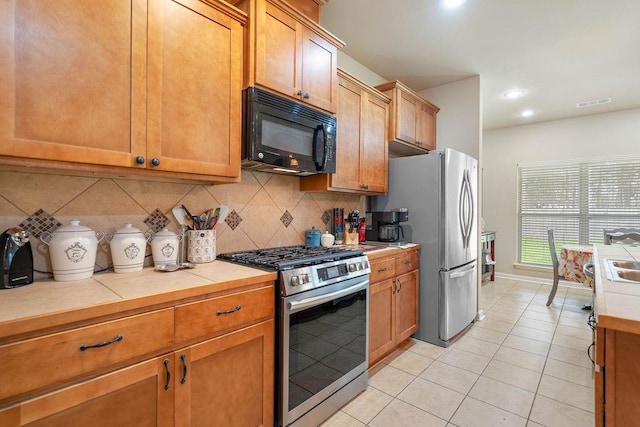 kitchen featuring tasteful backsplash, visible vents, tile counters, stainless steel appliances, and light tile patterned flooring