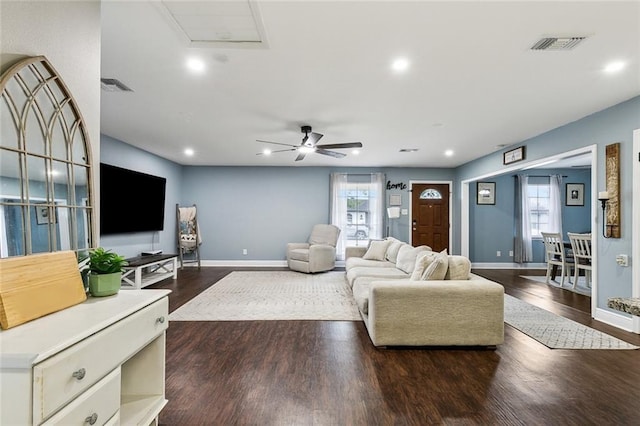 living room featuring dark wood-style flooring, plenty of natural light, visible vents, and baseboards