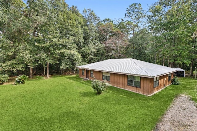 view of property exterior featuring metal roof, a lawn, and dirt driveway