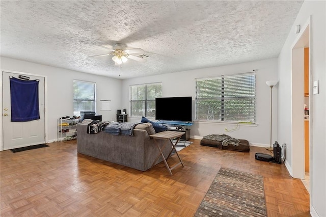 living area with a textured ceiling, visible vents, a ceiling fan, and baseboards