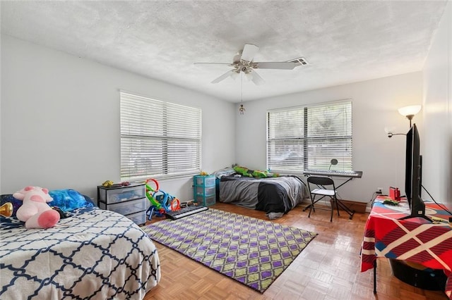 bedroom featuring a ceiling fan, visible vents, a textured ceiling, and baseboards