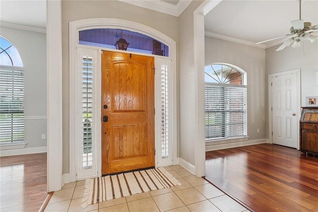 foyer entrance featuring crown molding, baseboards, and light tile patterned floors