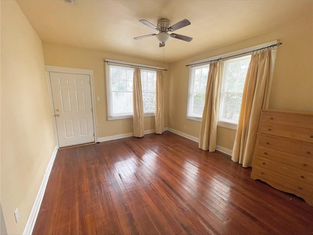 spare room featuring dark wood-type flooring, a ceiling fan, and baseboards