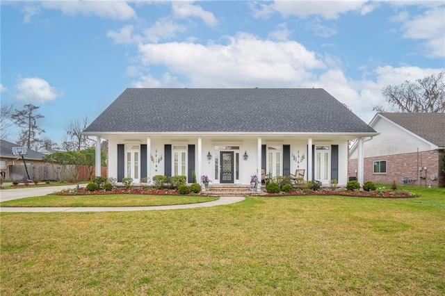 view of front facade featuring covered porch, roof with shingles, fence, and a front lawn