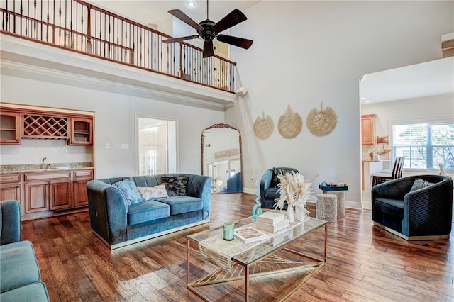 living area featuring dark wood-style floors, a high ceiling, baseboards, and indoor wet bar