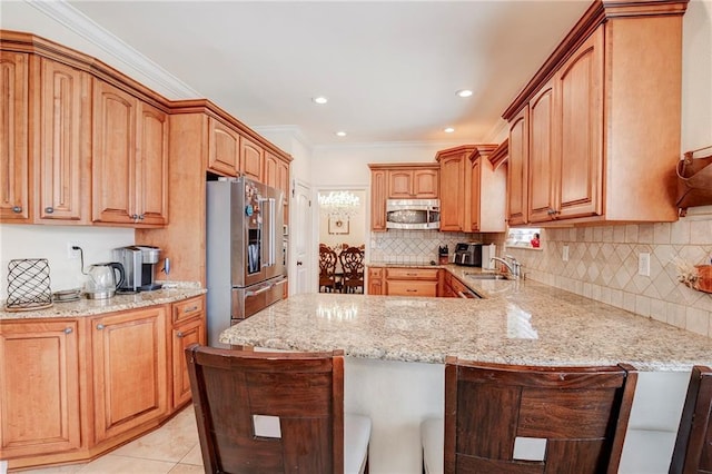 kitchen featuring stainless steel appliances, backsplash, a sink, light stone countertops, and a peninsula