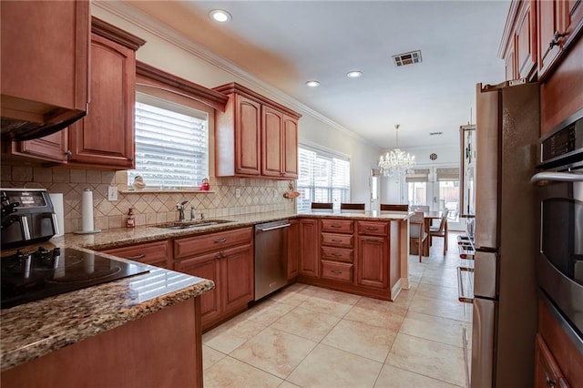 kitchen with visible vents, brown cabinetry, appliances with stainless steel finishes, decorative light fixtures, and a sink