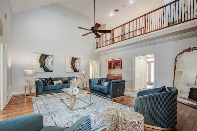 living room featuring baseboards, high vaulted ceiling, and wood finished floors