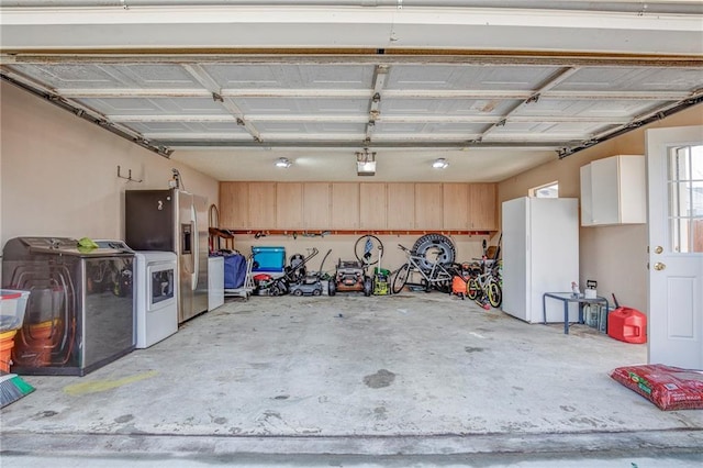 garage with a garage door opener, freestanding refrigerator, independent washer and dryer, and stainless steel refrigerator with ice dispenser