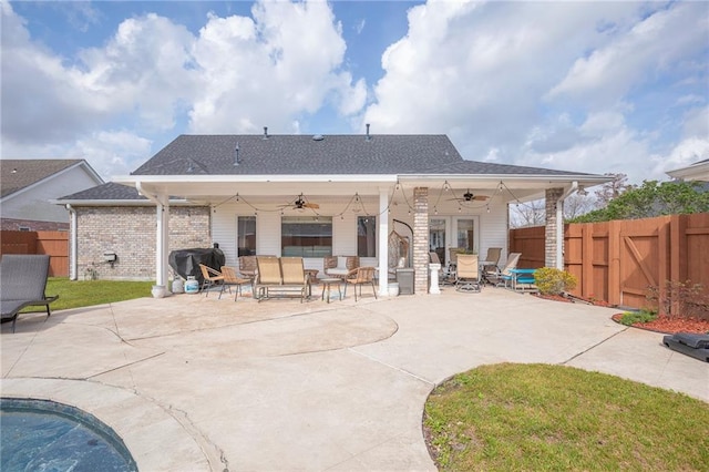 back of property with a fenced backyard, ceiling fan, brick siding, and a patio