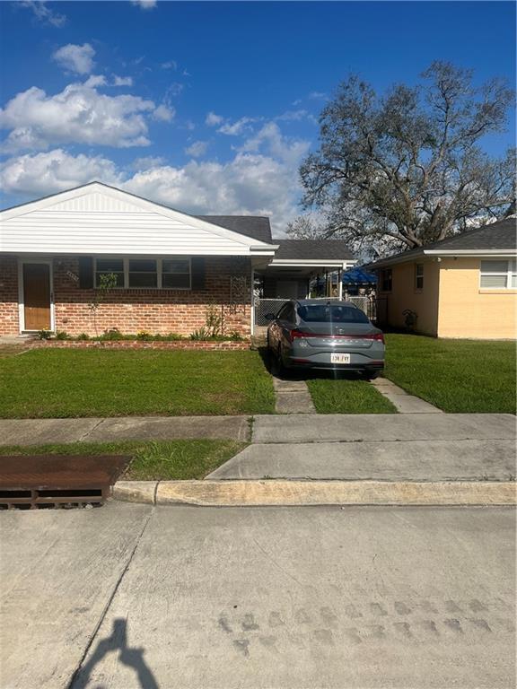 view of front facade with brick siding, driveway, and a front lawn