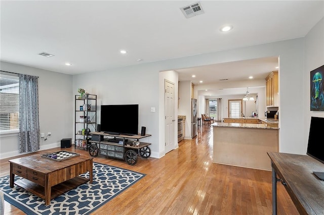 living room featuring light wood-style flooring, visible vents, and recessed lighting