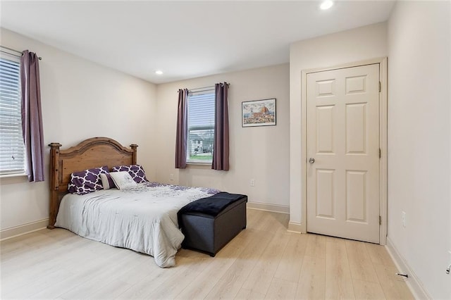 bedroom with light wood-type flooring, multiple windows, and baseboards