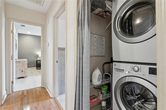 laundry room featuring visible vents, light wood-type flooring, stacked washing maching and dryer, and laundry area