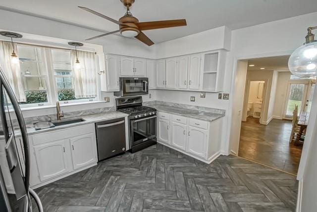 kitchen featuring open shelves, hanging light fixtures, appliances with stainless steel finishes, white cabinetry, and a sink