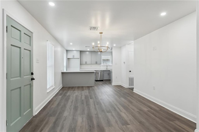 kitchen with pendant lighting, visible vents, light countertops, dark wood finished floors, and an inviting chandelier