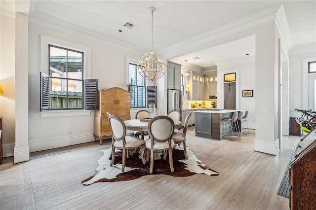 dining space with light wood-type flooring, plenty of natural light, visible vents, and ornamental molding