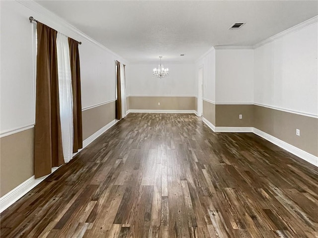 spare room with dark wood-style floors, visible vents, an inviting chandelier, ornamental molding, and baseboards