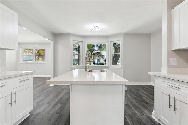 kitchen with baseboards, dark wood-type flooring, light countertops, white cabinetry, and a sink