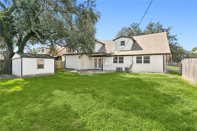 back of property with french doors, a lawn, an outdoor structure, and fence