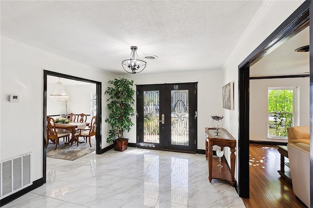 entryway featuring a chandelier, french doors, visible vents, and a textured ceiling