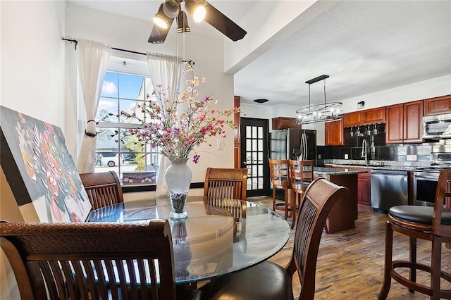 dining room featuring dark wood-style floors and ceiling fan with notable chandelier