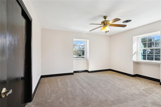 empty room with baseboards, visible vents, and light colored carpet