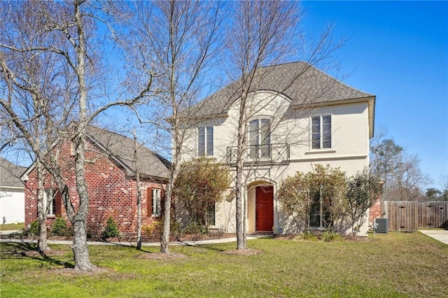 view of front of property with stucco siding, fence, a front lawn, and central air condition unit