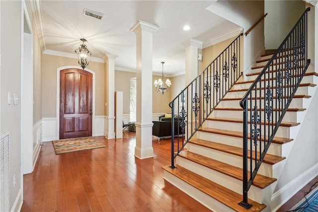 entryway with crown molding, visible vents, decorative columns, and wood finished floors