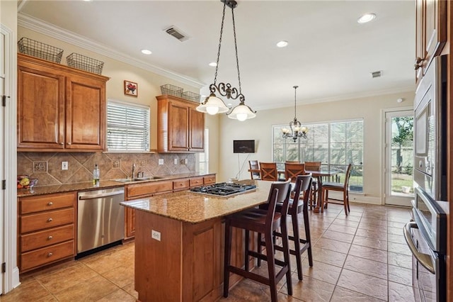 kitchen featuring a center island, pendant lighting, brown cabinets, appliances with stainless steel finishes, and a sink