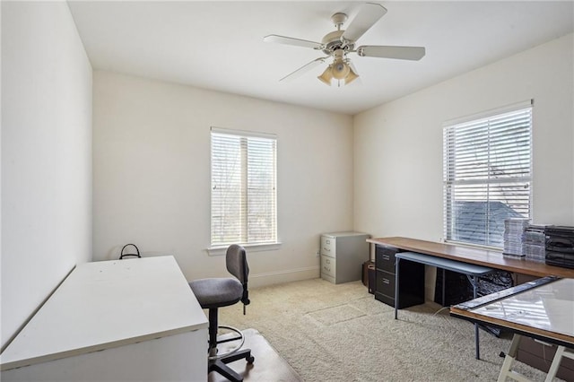 office featuring light colored carpet, ceiling fan, and baseboards