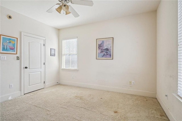 empty room with baseboards, a ceiling fan, and light colored carpet