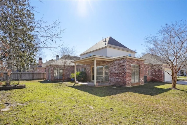 rear view of property with a garage, a yard, brick siding, and fence