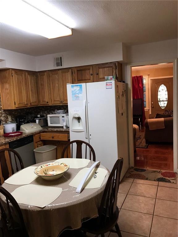 kitchen featuring dark countertops, white appliances, visible vents, and brown cabinets