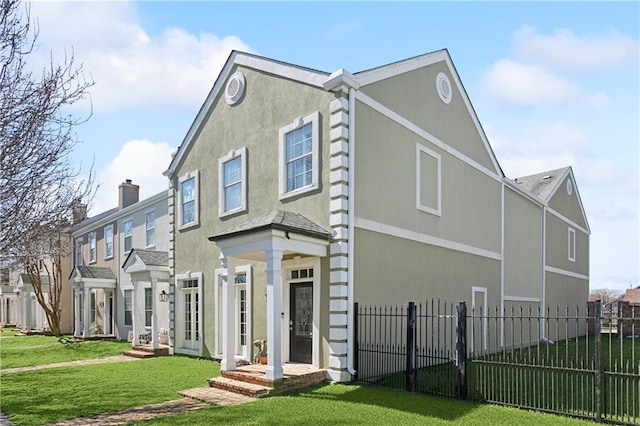 view of front of home featuring a fenced front yard, a chimney, a front lawn, and stucco siding