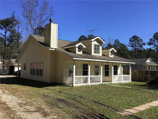 back of property with covered porch, a chimney, and a lawn