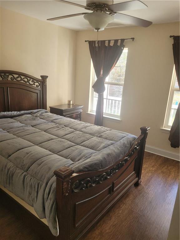 bedroom featuring a ceiling fan, dark wood finished floors, and baseboards