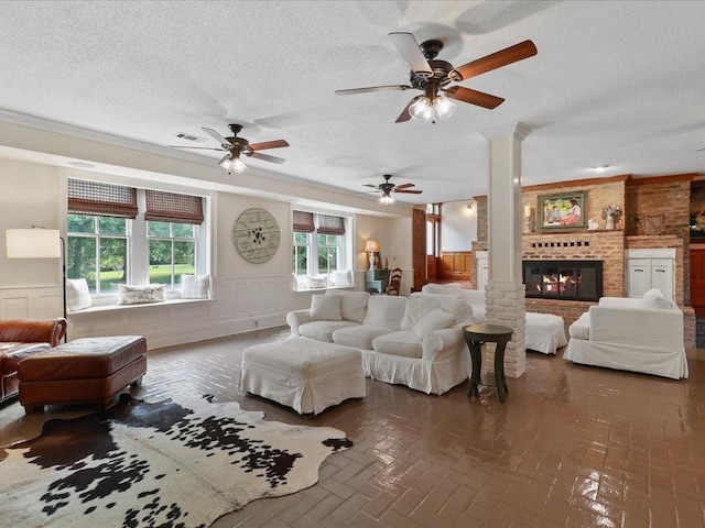 living area with a brick fireplace, a textured ceiling, and wainscoting