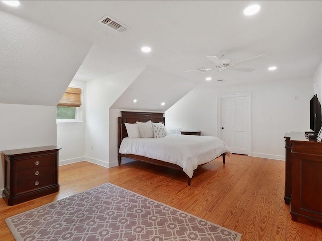 bedroom with light wood-style floors, visible vents, and vaulted ceiling