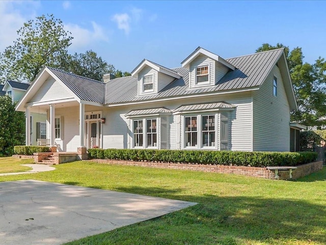 view of front of property featuring metal roof, a front lawn, and covered porch